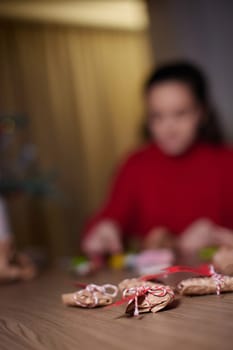 Christmas gifts on table and woman wrapping Christmas gifts at background, focus on gifts