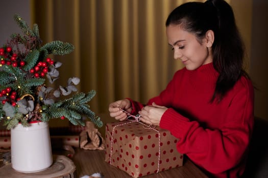 woman wrapping Christmas gifts at home in the evening, preparing presents for family.