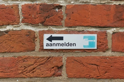 Sign with the Dutch inscription aanmelden at a hotel in Bruges, Belgium. Translation: log in, register