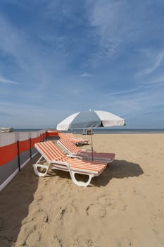 Sun lounger and parasol on the popular beach of De Haan on the North Sea in Belgium