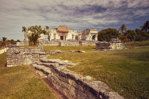 Scenic view of ancient mayan ruins at tulum archaeological site, showcasing weathered stone structures, lush vegetation, and a serene coastal backdrop