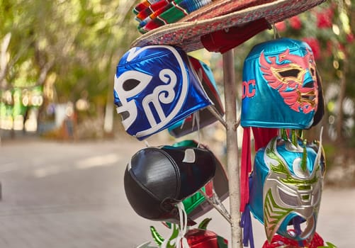 Colorful lucha libre masks and sombreros are displayed on a metal rack in tulum, mexico, offering a vibrant glimpse into mexican culture