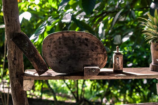 Rustic charm of traditional dominican kitchenware displayed on a weathered wooden shelf amidst a backdrop of vibrant tropical foliage in montana redonda