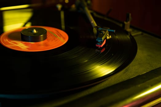 Close-up of a vintage turntable playing a vinyl record with red label, illuminated by warm, atmospheric lighting