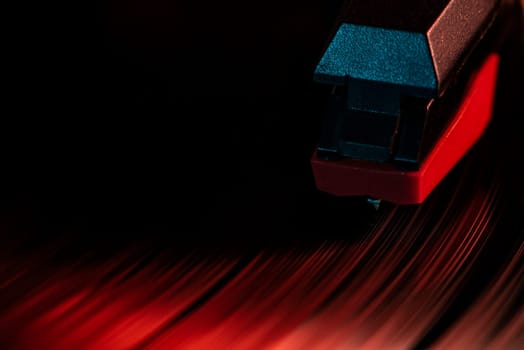 Close-up of a record player needle reading a vinyl record illuminated by red light, creating a dramatic and nostalgic atmosphere