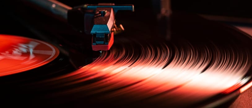 Close-up of a spinning vinyl record playing on a turntable, illuminated by a vibrant red light, creating a mesmerizing visual effect