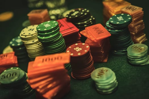 Colorful poker chips and plaques stacked high on a green felt table create an exciting gambling atmosphere