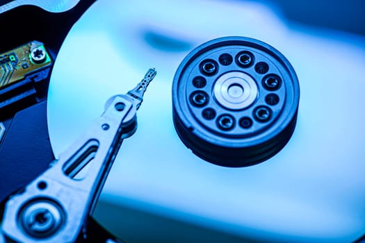 Hard disk drive reading data with blue light, macro close-up of actuator arm and disk surface