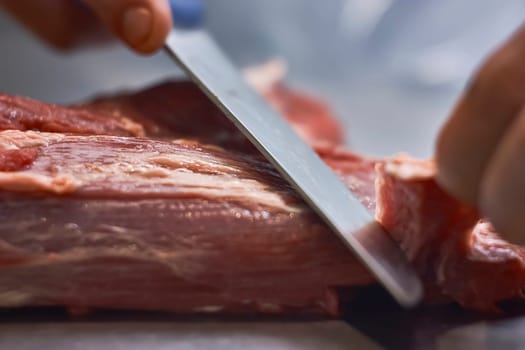 Close-up of butcher carefully slicing red meat with a sharp knife, emphasizing precision and freshness in a professional butchery setting