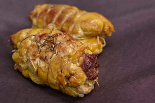 Two appetizing stuffed chicken breasts, seasoned with rosemary, resting on a dark background