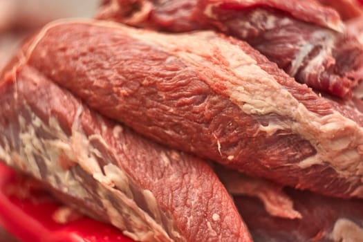 Close-up of fresh, raw red meat, showcasing its texture and color, ready for preparation in a butcher shop