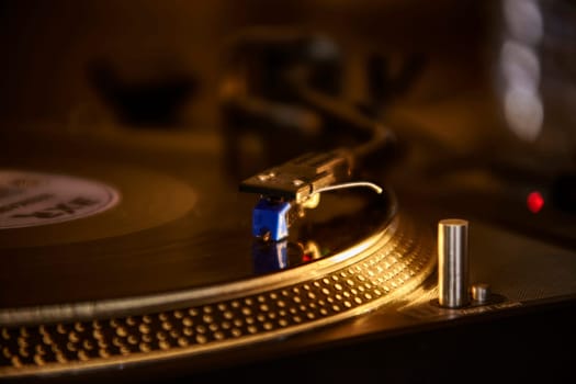 Close-up of a turntable playing a vinyl record, the needle gently tracing the grooves of the spinning disc in a warm, dimly lit setting