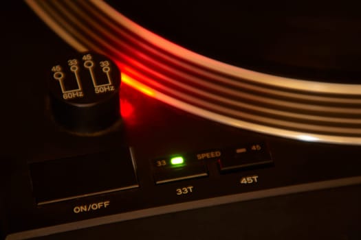 Close-up of a vintage turntable playing a vinyl record, illuminated by a red light, creating a warm and nostalgic atmosphere