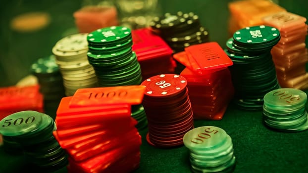 Stacks of poker chips and plaques rest on a green felt table, representing gambling, betting, and casino games