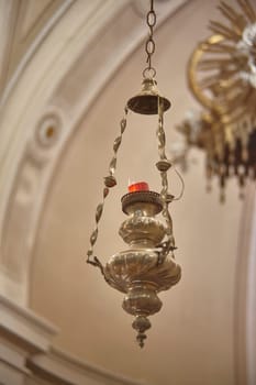 Ornate votive lamp illuminates a church, symbolizing faith, hope, and devotion in a sacred space
