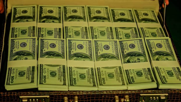 Briefcase overflowing with stacks of bundled one hundred us dollar bills, suggesting wealth, success, and finance