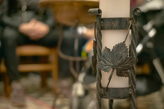 Close up of a wrought iron candle holder decorated with grape leaves, adding a touch of nature to a church setting