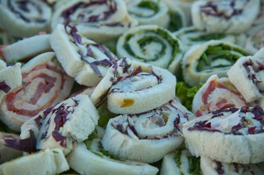 Close-up of pinwheel sandwiches, showcasing a variety of fillings including ham, cheese, and vegetables, ready to be enjoyed