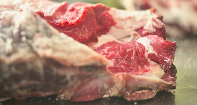 Close-up of butcher cutting fresh red meat on a metal table, showcasing the preparation process