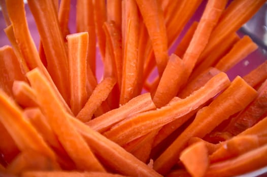 Vibrant orange carrot sticks are piled high in a pink bowl, ready to be enjoyed as a healthy snack or used as a fresh ingredient in various dishes