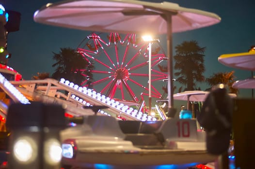 Glowing ferris wheel and colorful amusement park rides light up the night sky