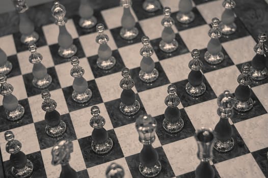Elegant glass chess pieces are arranged on a marble chessboard, creating a sophisticated and strategic scene