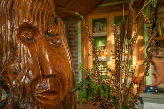 Wooden sculpture adds a touch of artistry to a rustic shop, complemented by dried plants and jars of honey displayed in the background
