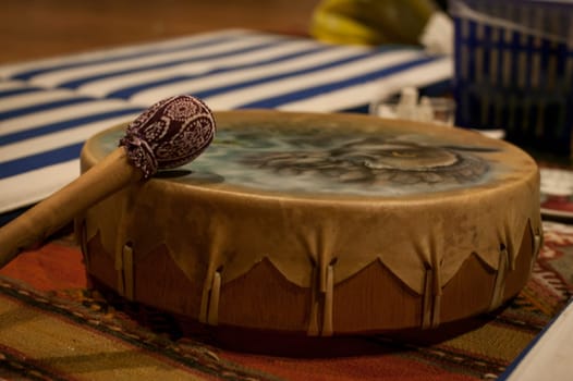 Traditional native american drum with mallet resting on a colorful rug, evoking cultural heritage and music