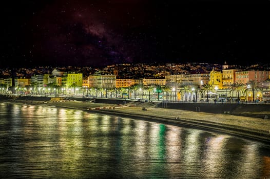 City lights reflecting in the mediterranean sea along the promenade des anglais in nice, france, at night under a starry sky
