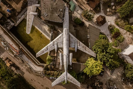 Aerial view of an abandoned, weathered airplane resting in a residential backyard, showcasing urban decay and repurposing of space