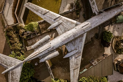 Aerial view of a weathered and decaying airplane resting on the ground in an abandoned urban area