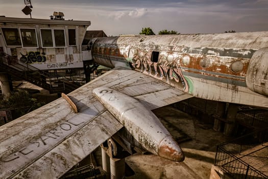 Decaying airplane fuselage covered in graffiti, illustrating urban decay and the passage of time