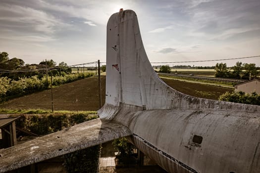 Weathered tail of an abandoned airplane dominates the view of the italian countryside