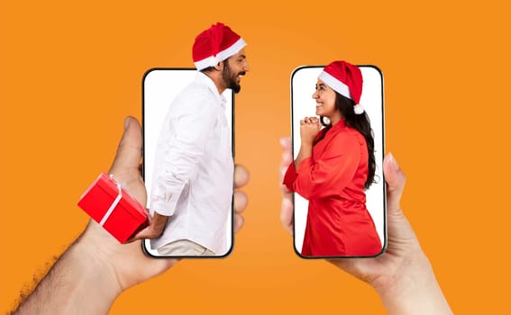 Two individuals, wearing Santa hats, playfully interact through their smartphones, sharing love and connection. They seem joyful while preparing festive surprises for each other.