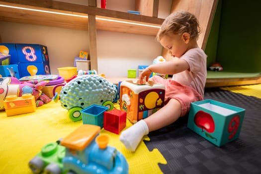 Toddler engaged with building blocks and interactive toys in a cheerful play area