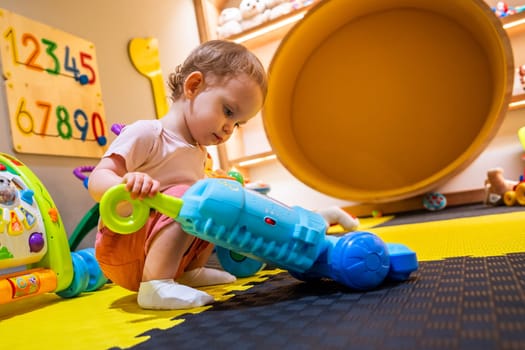 Toddler cleaning with a toy vacuum cleaner in a colorful playroom for early childhood development and learning activities