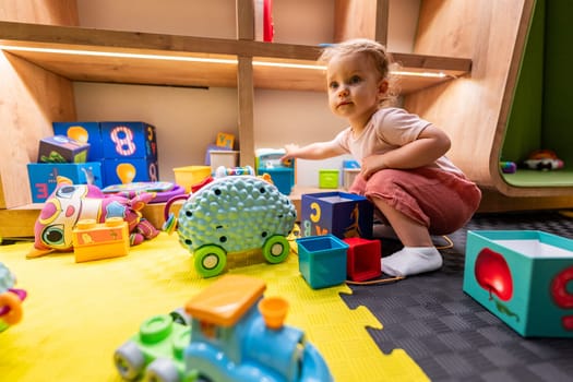 Toddler engaged with educational blocks and toys in a vibrant and cheerful play area