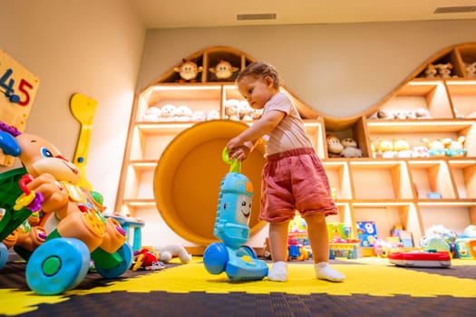 Kid having fun with a toy vacuum cleaner in a bright playroom designed for creativity and motor skill training