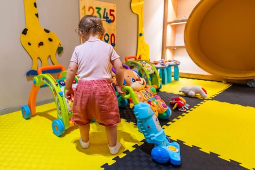 Little girl practicing cleaning skills with a toy vacuum cleaner in a bright and playful indoor playroom