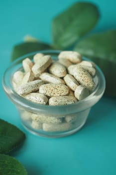 Herbal tablets showcased in a glass bowl, complemented by green leaves for a beautiful presentation