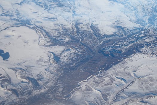 A stunning aerial image shows breathtaking snowy mountains and valleys under clear skies