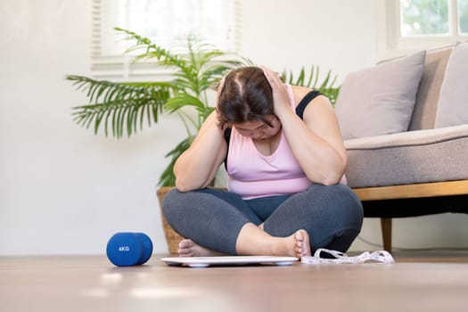 An individual sits on the floor overwhelmed by weight and emotions reflecting on their fitness journey and struggles with self-image.