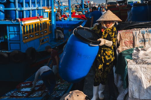 A Vietnamese woman unloads fresh fish for sale at a fish market. Vietnam, Nha Trang - September 8, 2024