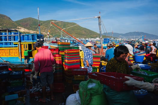 Unidentified Asian workers collect fish from fishing boats to sell in an old fishing harbor. Vietnam, Nha Trang - September 8, 2024