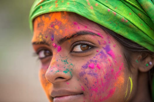 Portrait of happy young indian woman on holi festival with gulal powder on her face. Girl celedtating Holi, Indian festival of color
