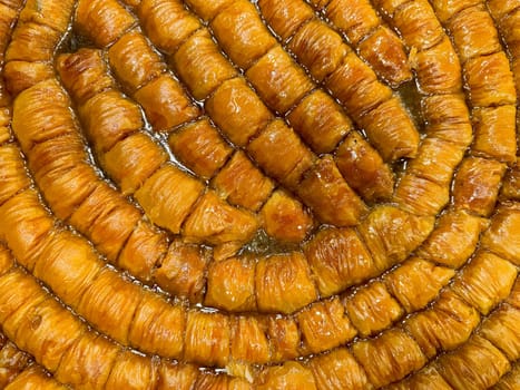 Solid background of freshly baked baklava laid out in rows, golden brown with syrup glaze, traditional Middle Eastern sweet pastry dessert, close up texture. Ramadan concept. High quality photo