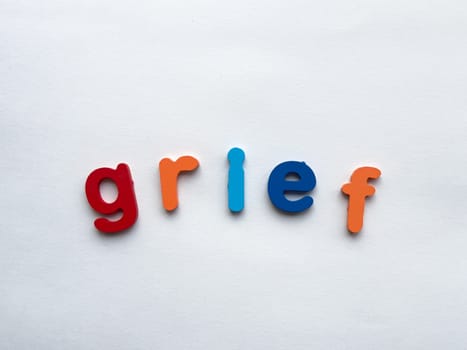 Colorful letters spelling grief on white background.