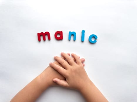 Childs hands with colorful letters manic on white background.