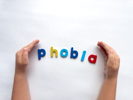 Colorful letters forming the word phobia with hands on a white background.