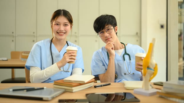 Smiling medical students in scrubs taking a relaxing pause from their studies in campus.
